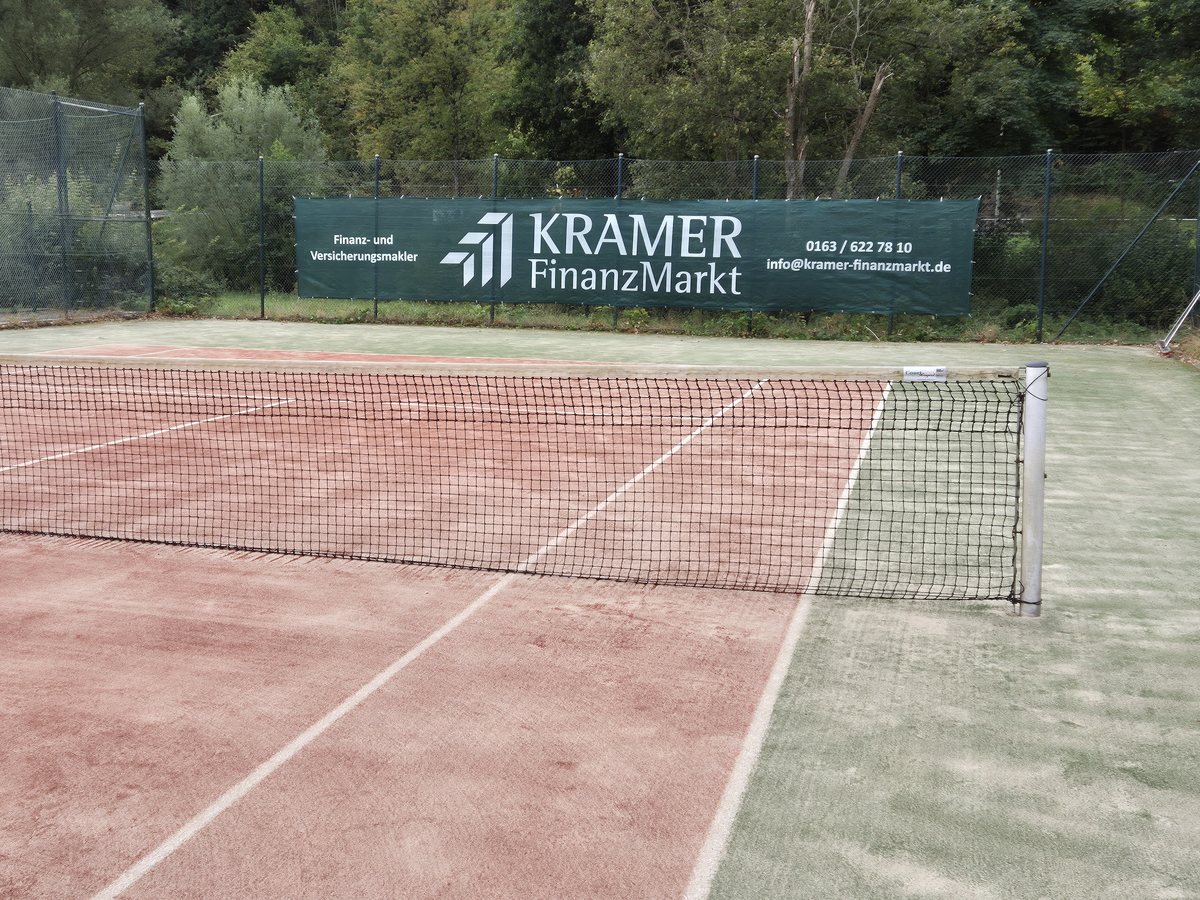 Tennisplatz des TC Rot-Weiss Kirchhundem, im Hintergrund das Banner von KRAMER FinanzMarkt am Zaun