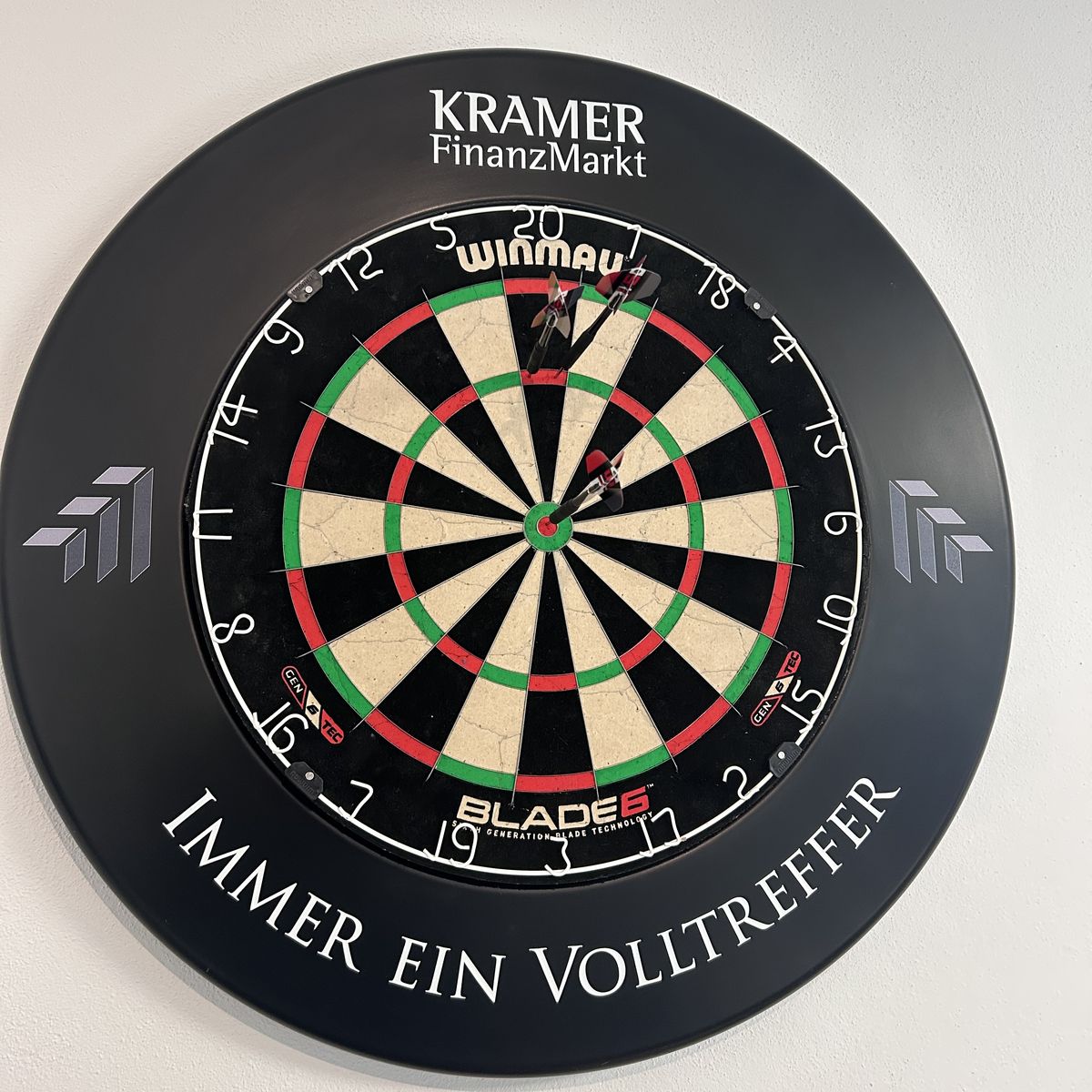 Dartscheibe mit KRAMER-FinanzMarkt-Umrandung und dem Spruch Immer ein Volltreffer